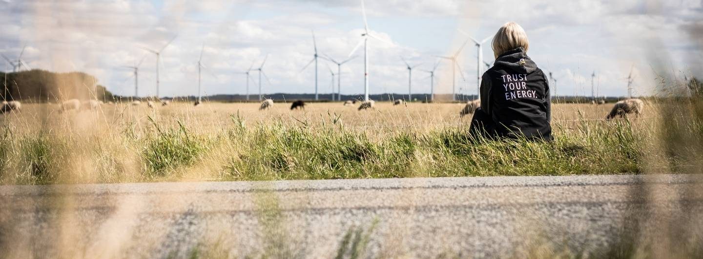 Eine Frau schaut auf Windräder in der Ferne. Das Erneuerbare Energien Gesetz: Wieso, weshalb, warum