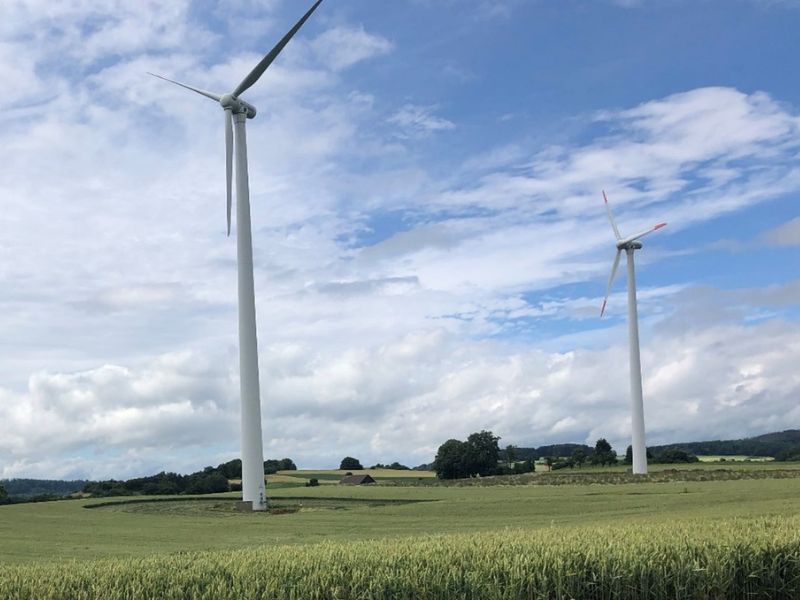 Zwei Windenergieanlagen in der Landschaft.