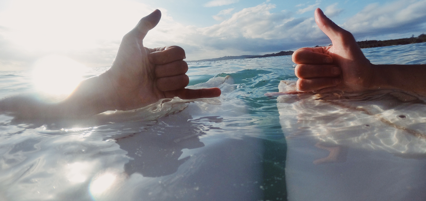 Zwei Hände machen eine Geste der Surfer.