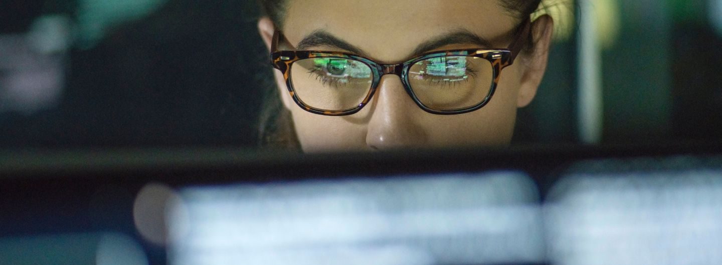 Eine Frau mit Brille schaut auf einen Monitor.