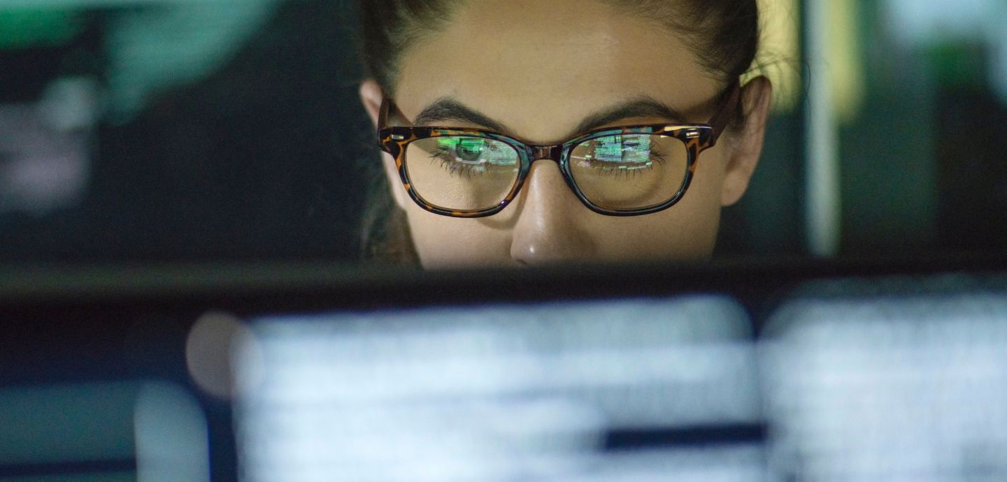 Eine Frau mit Brille schaut auf einen Monitor.