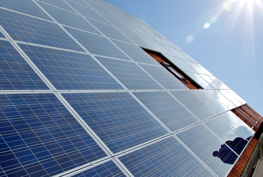 Das Bild zeigt einen Menschen neben einer Photovoltaik-Anlage auf einem Dach.