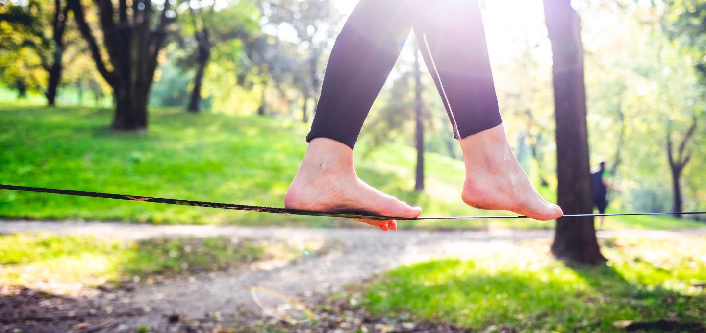 Die Füße eines Menschen balancieren in der Natur auf einem Seil.