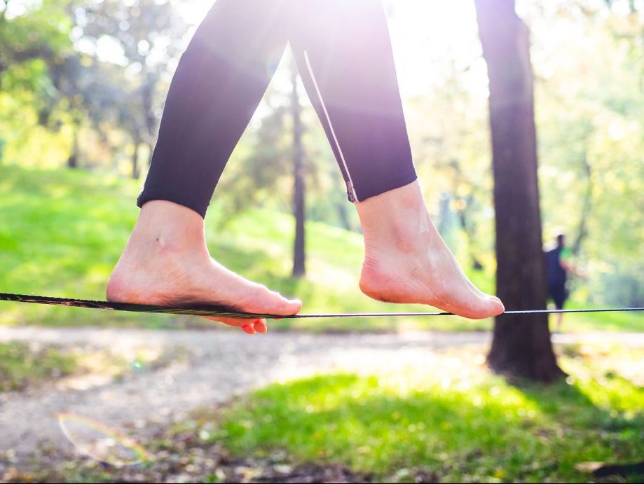 Die Füße eines Menschen balancieren in der Natur auf einem Seil.
