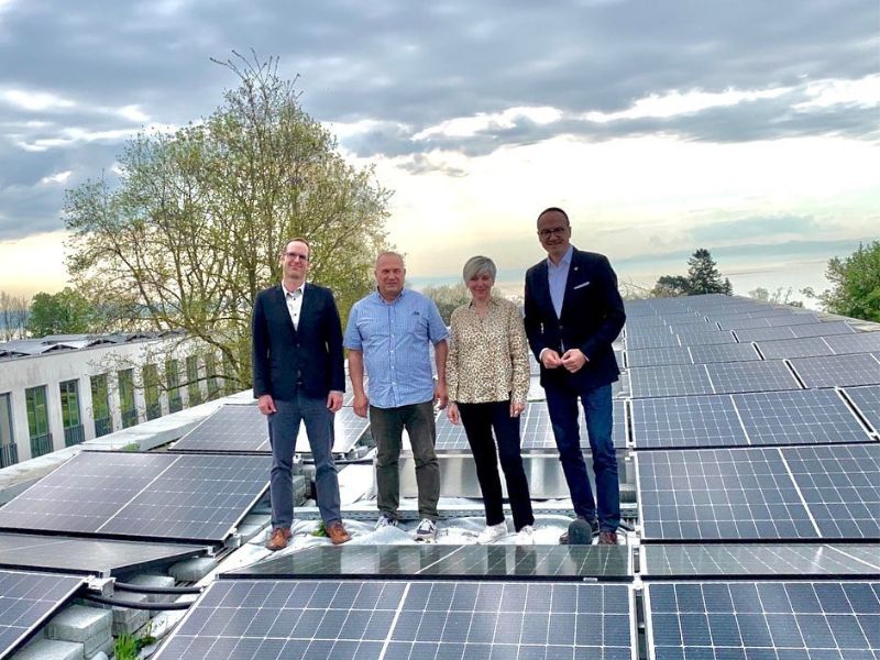 Das Foto zeigt vier Menschen auf einem Dach mit Photovoltaikanlage.
