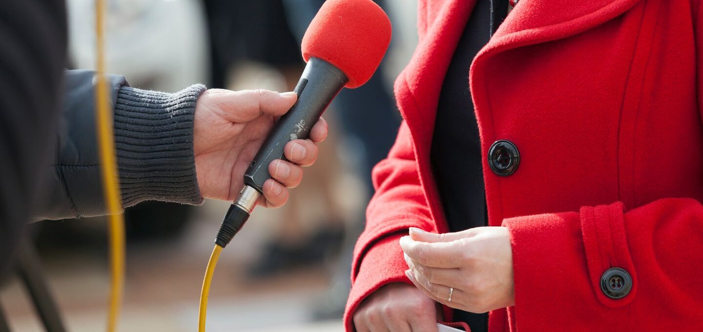 Interviewsituation: Einer Frau wird ein Mikrofon vorgehalten.