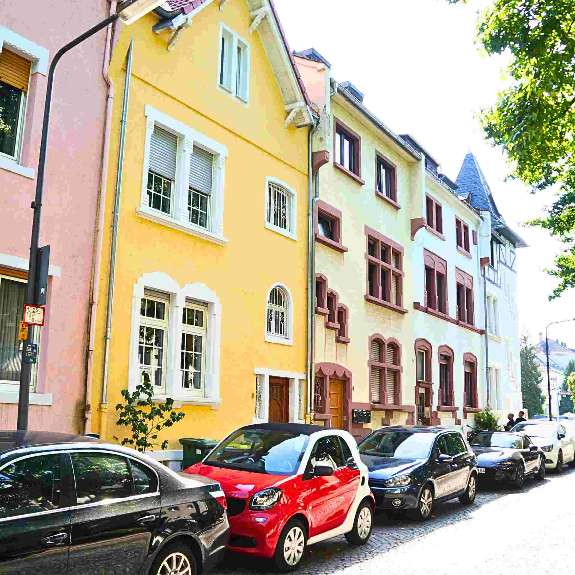 eine Straßenansicht mit Häusern und Autos bei Sonnenschein