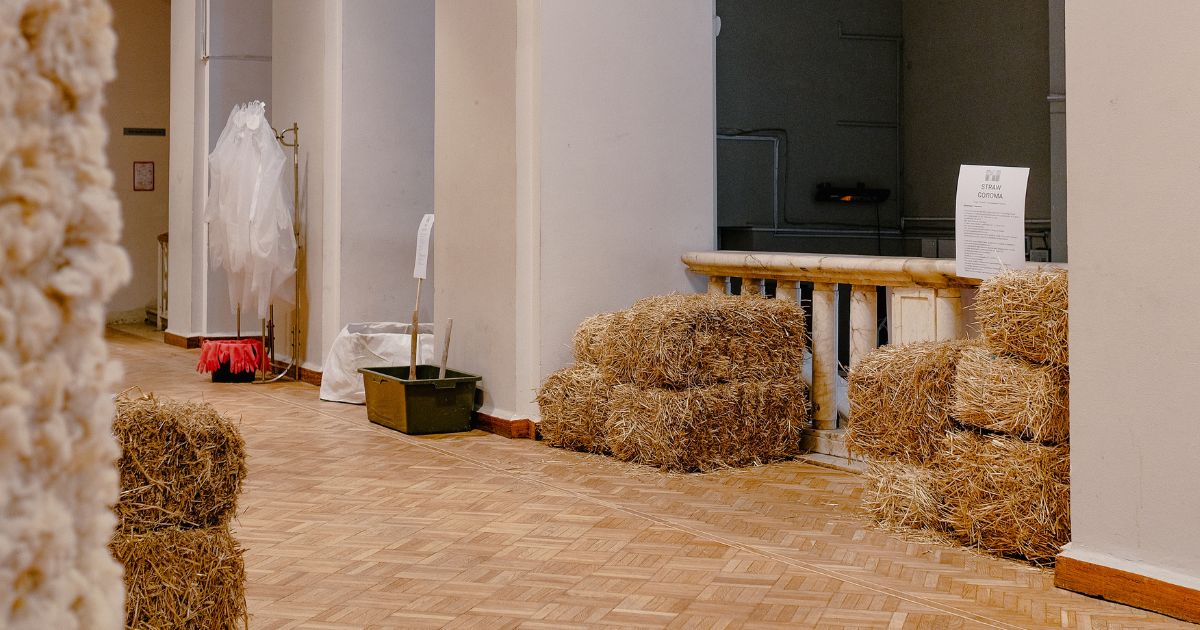 Blick in die Ausstellung: Man sieht Heuballen, einen Kronleuchter, Naturmaterialien.