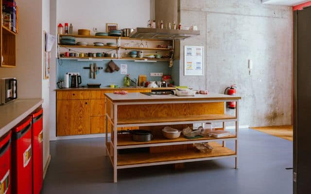 Offene Gemeinschaftsküche mit einer Kücheninsel und viel Licht von draußen.