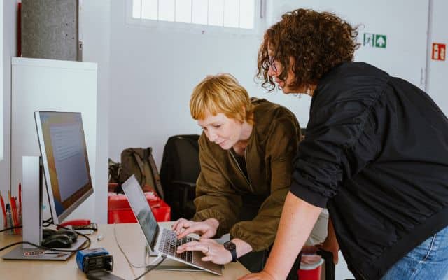 Die Geschäftsführerinnen der Smart Genossenschaft für Soloselbstständige Alicia Möltner und Magdalena Ziomek beugen sich gemeinsam über einen Laptop